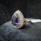 Ring with a blue gemstone and diamond stones on a textured black surface