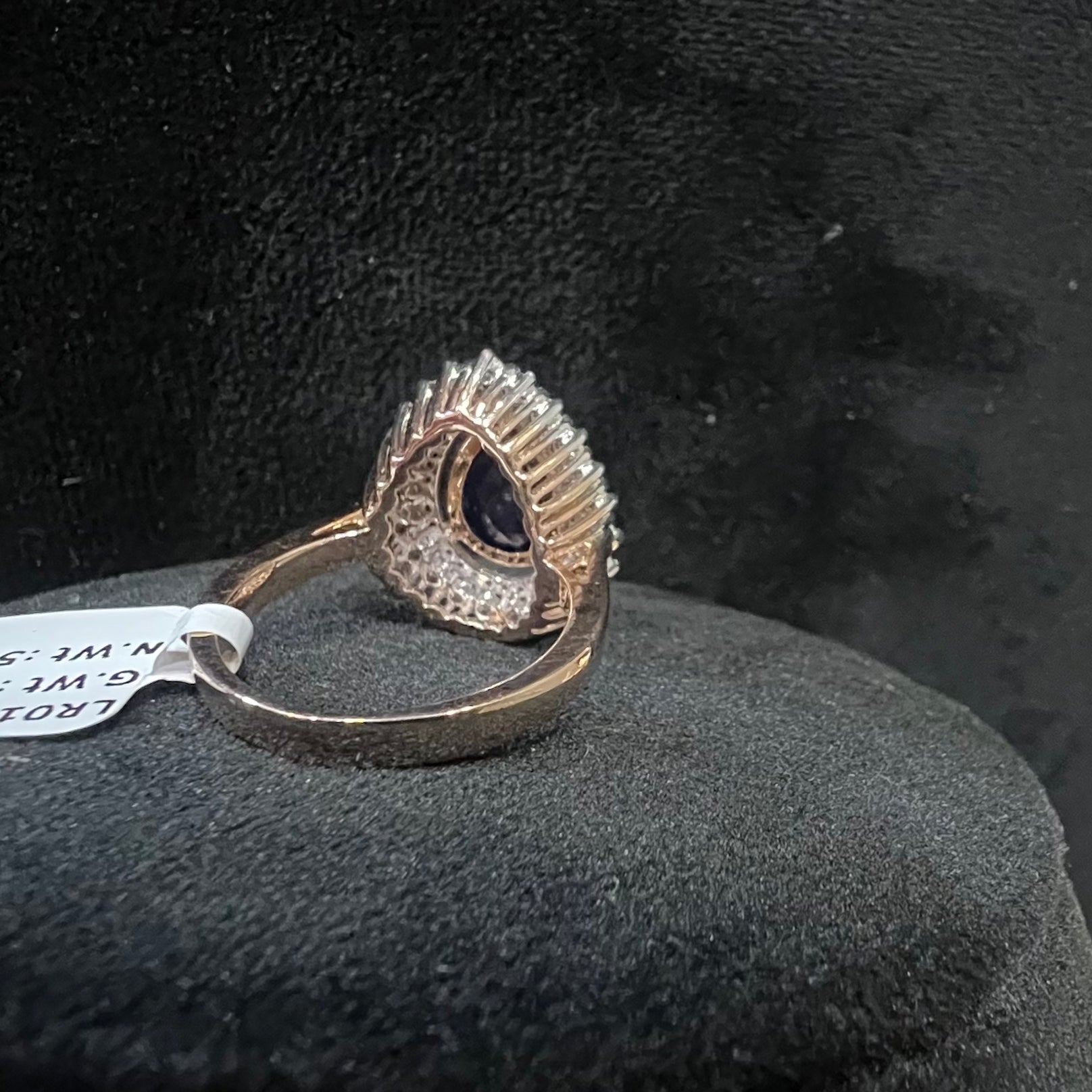 Gold diamond ring with a gemstone on a black cushion