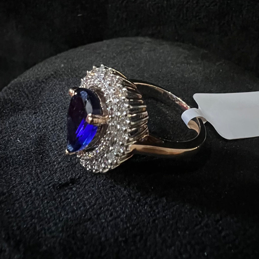 Gold diamond ring with a blue gemstone on a black surface