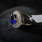 Gold diamond ring with a blue gemstone on a black surface