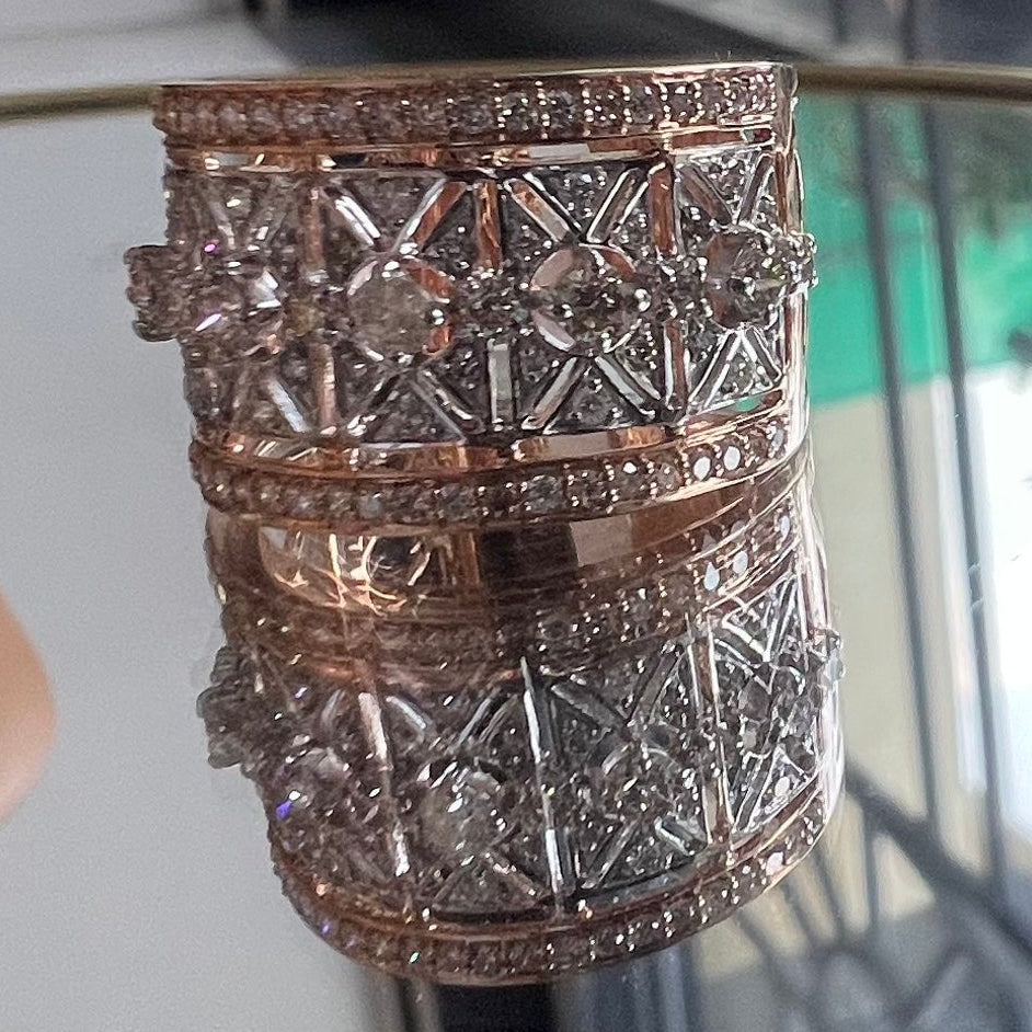 Gold and diamond ring with intricate design on a reflective surface