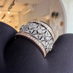 Diamond ring held in dark gloves with a blurred indoor background