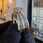 Gold and diamond ring held by a gloved hand with a blurred background
