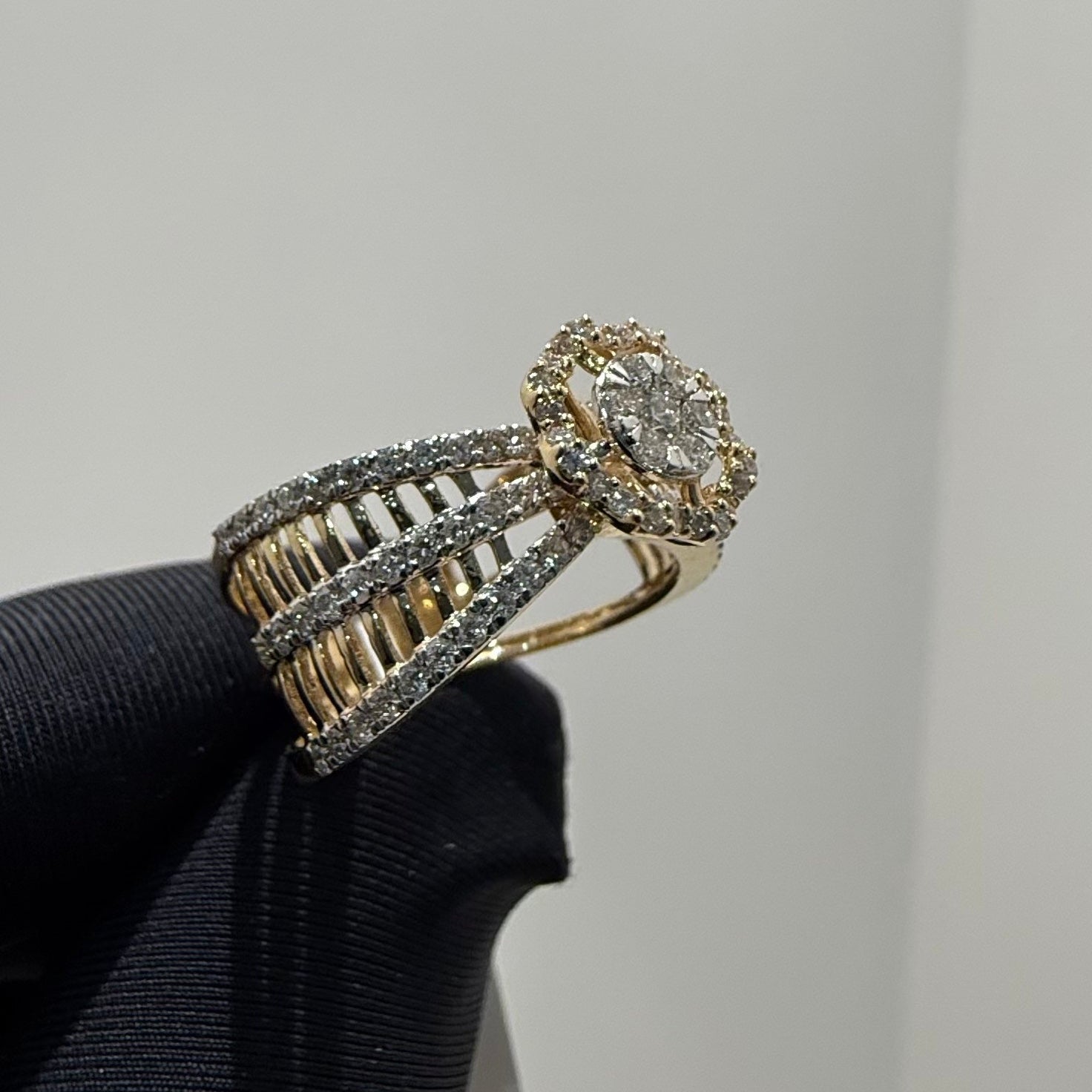 Gold ring with diamond accents on a black stand against a gray background