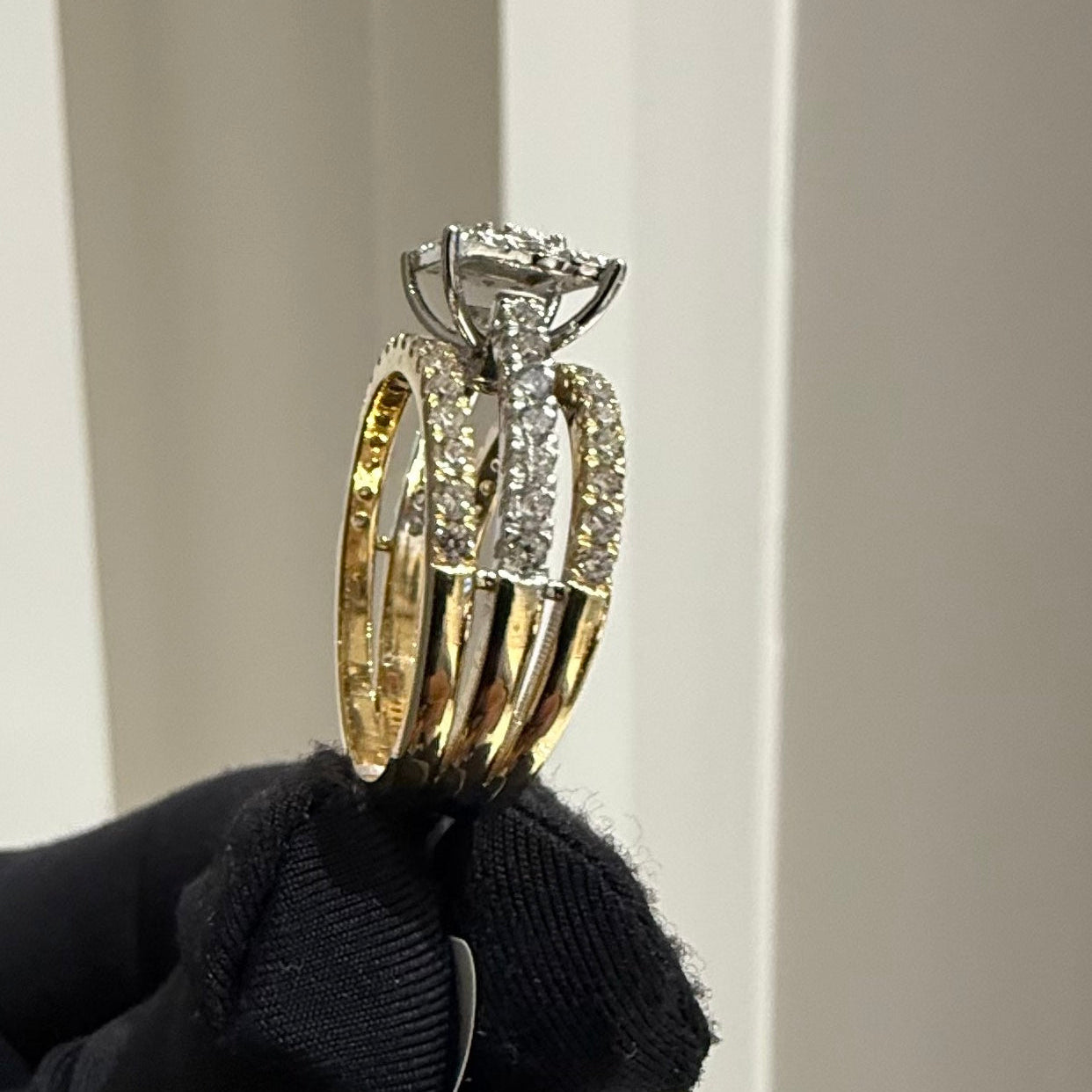 Diamond ring held by a gloved hand against a neutral background