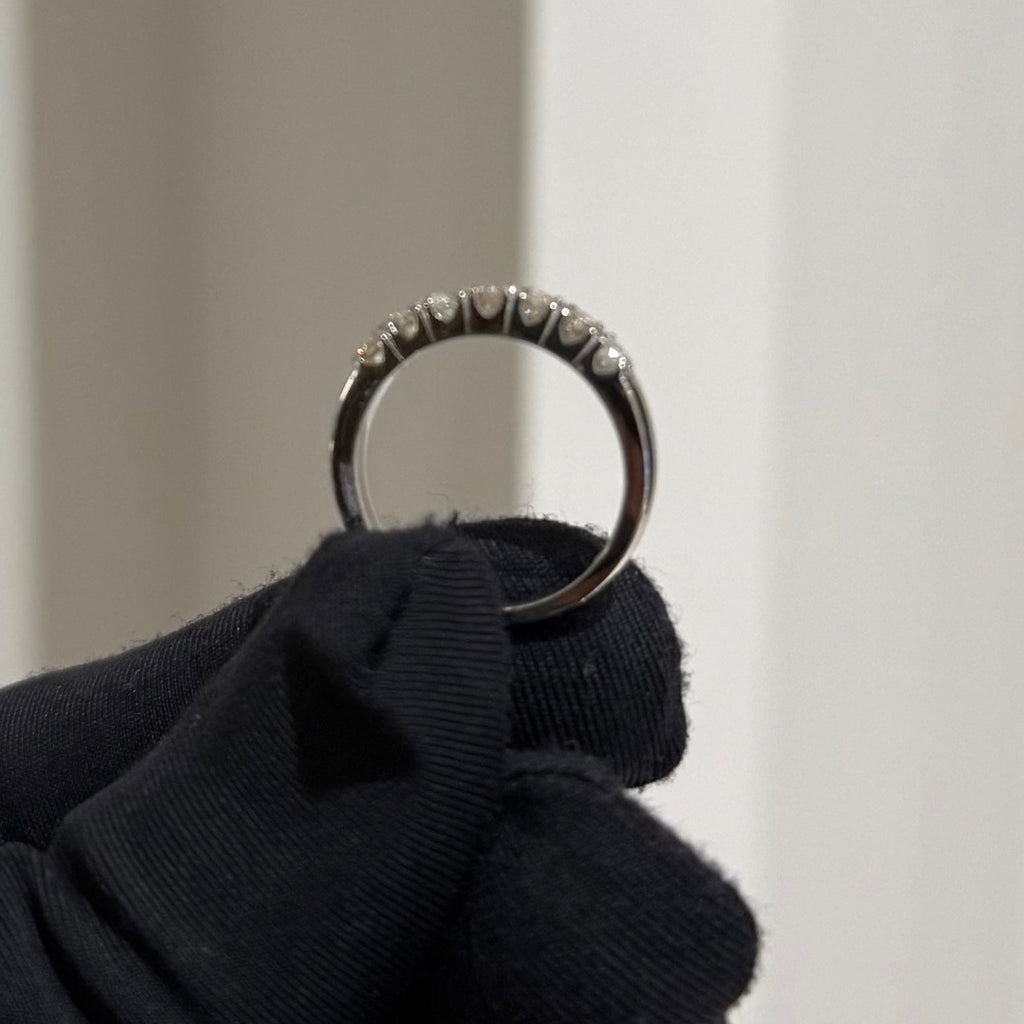 Gold ring held by a gloved hand against a neutral background