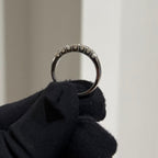 Gold ring held by a gloved hand against a neutral background