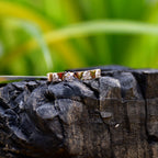 Gold rings with small diamonds on a wooden surface with a blurred green background