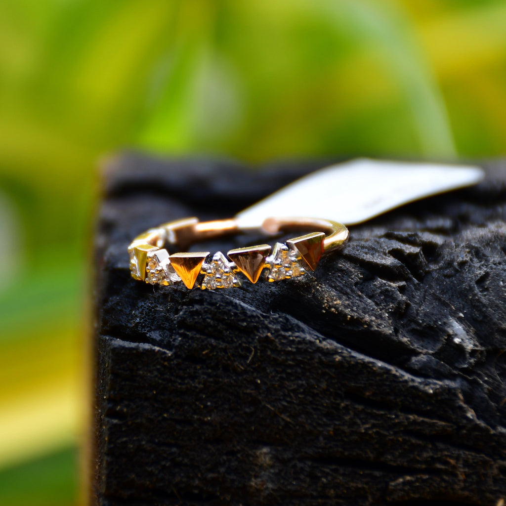 Gold ring with small diamonds on a dark stone surface with a blurred green background