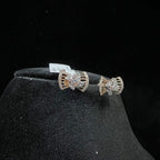 Pair of bow-shaped diamond earrings on a black stand with a dark background