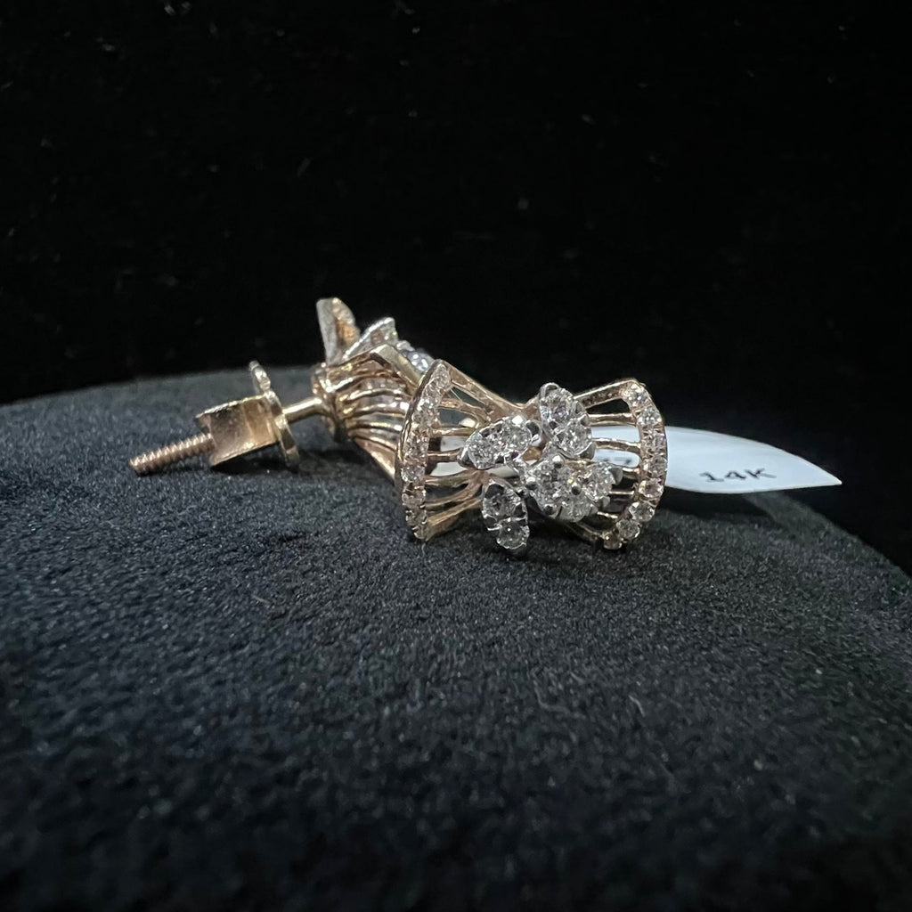 Pair of diamond earrings on a black surface with a dark background