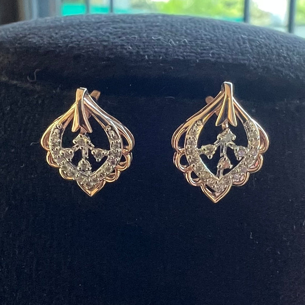 Pair of gold and diamond earrings on a black velvet stand.
