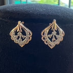 Pair of gold and diamond earrings on a black velvet stand.