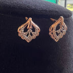 Pair of rose gold earrings with diamond accents on a black cushion