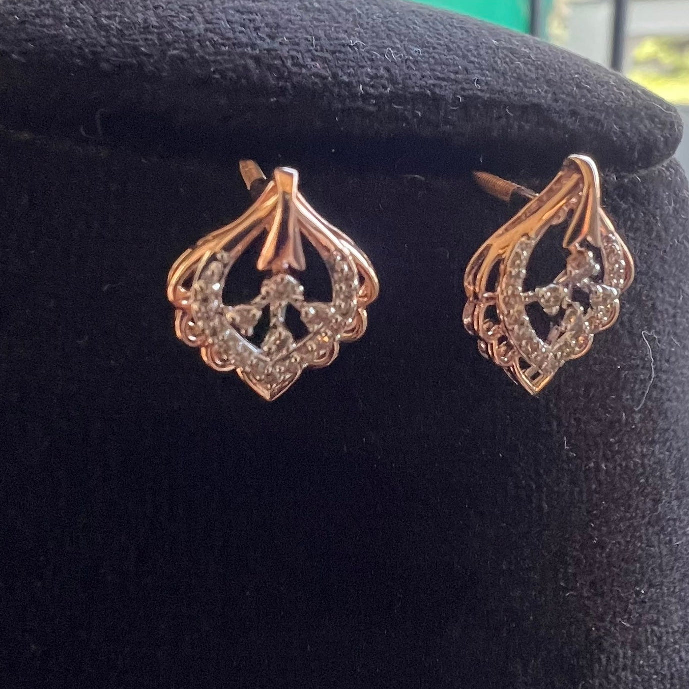 Pair of rose gold earrings with diamond accents on a black cushion