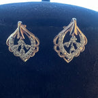 Pair of gold earrings with diamonds on a dark blue cushion