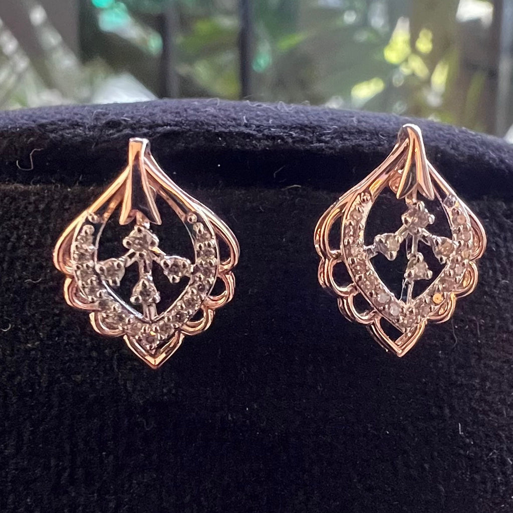 Pair of rose gold earrings with intricate designs on a black background