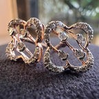Pair of ornate diamond earrings with intricate designs on a dark textured surface.