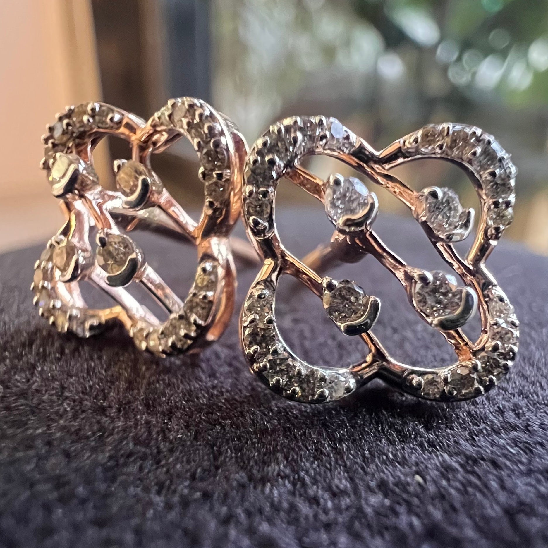Pair of ornate diamond earrings with intricate designs on a dark textured surface.