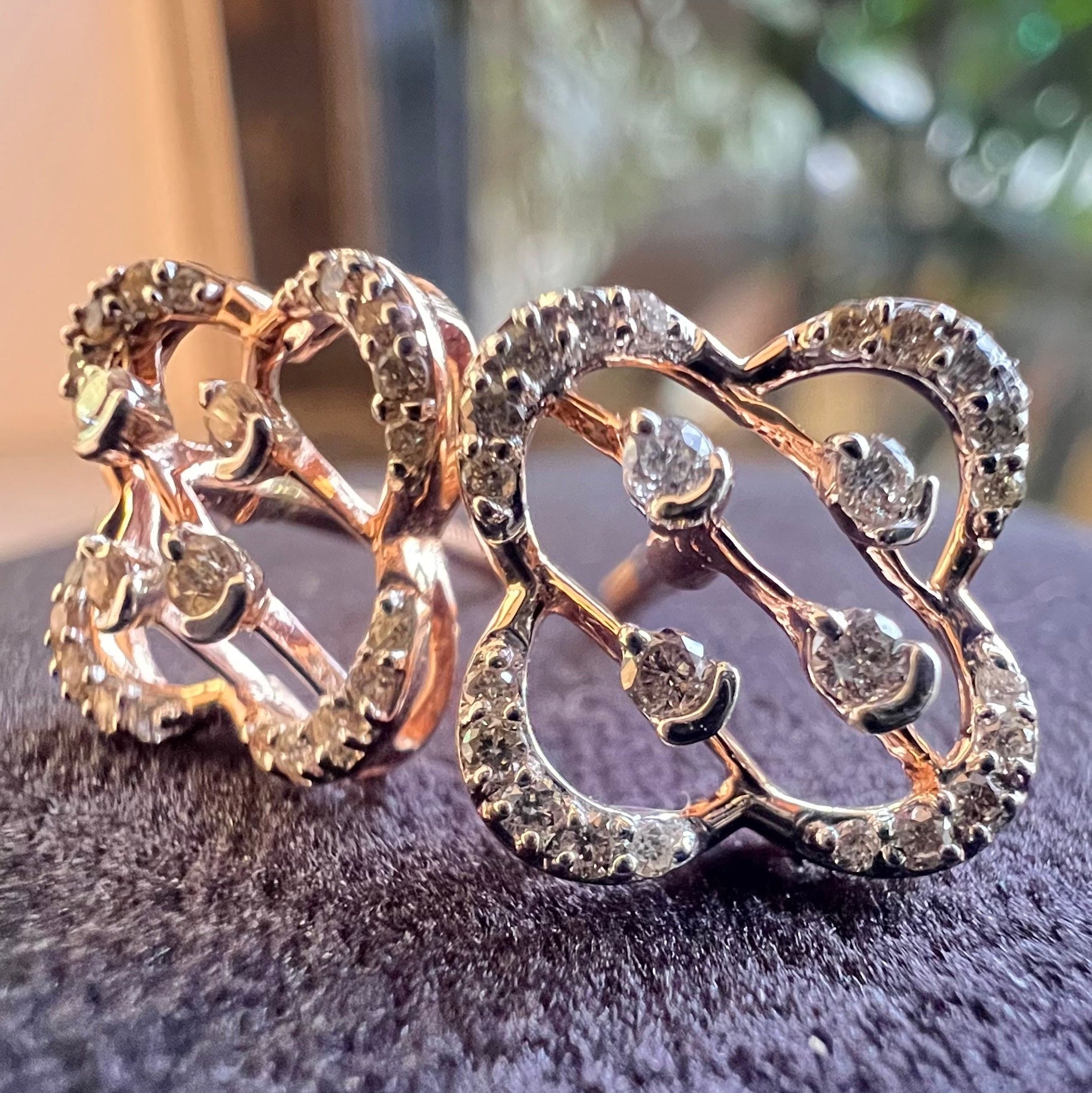 Rose gold butterfly-shaped earrings with embedded diamonds on a dark surface.