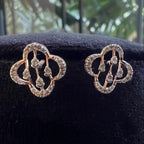 Pair of diamond earrings on a black cushion with a blurred green background