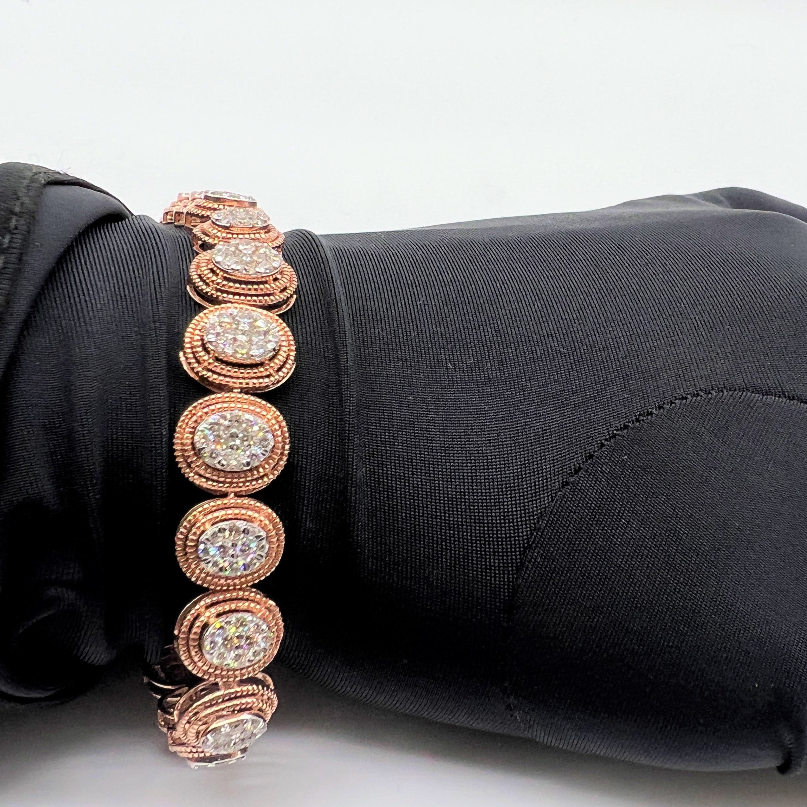 Rose gold diamond bracelet with circular designs on a black fabric background
