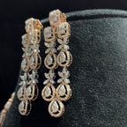 Pair of gold and diamond earrings on a black stand.