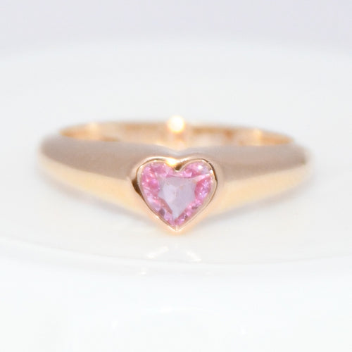 Gold ring with a pink heart-shaped gemstone on a white background