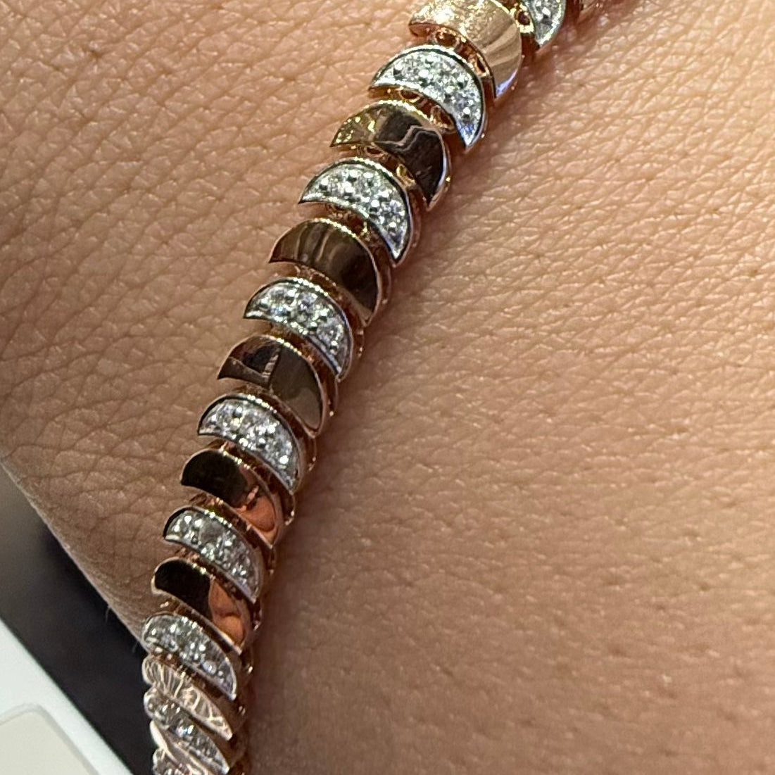 Gold and diamond bracelet on a person's wrist against a beige background