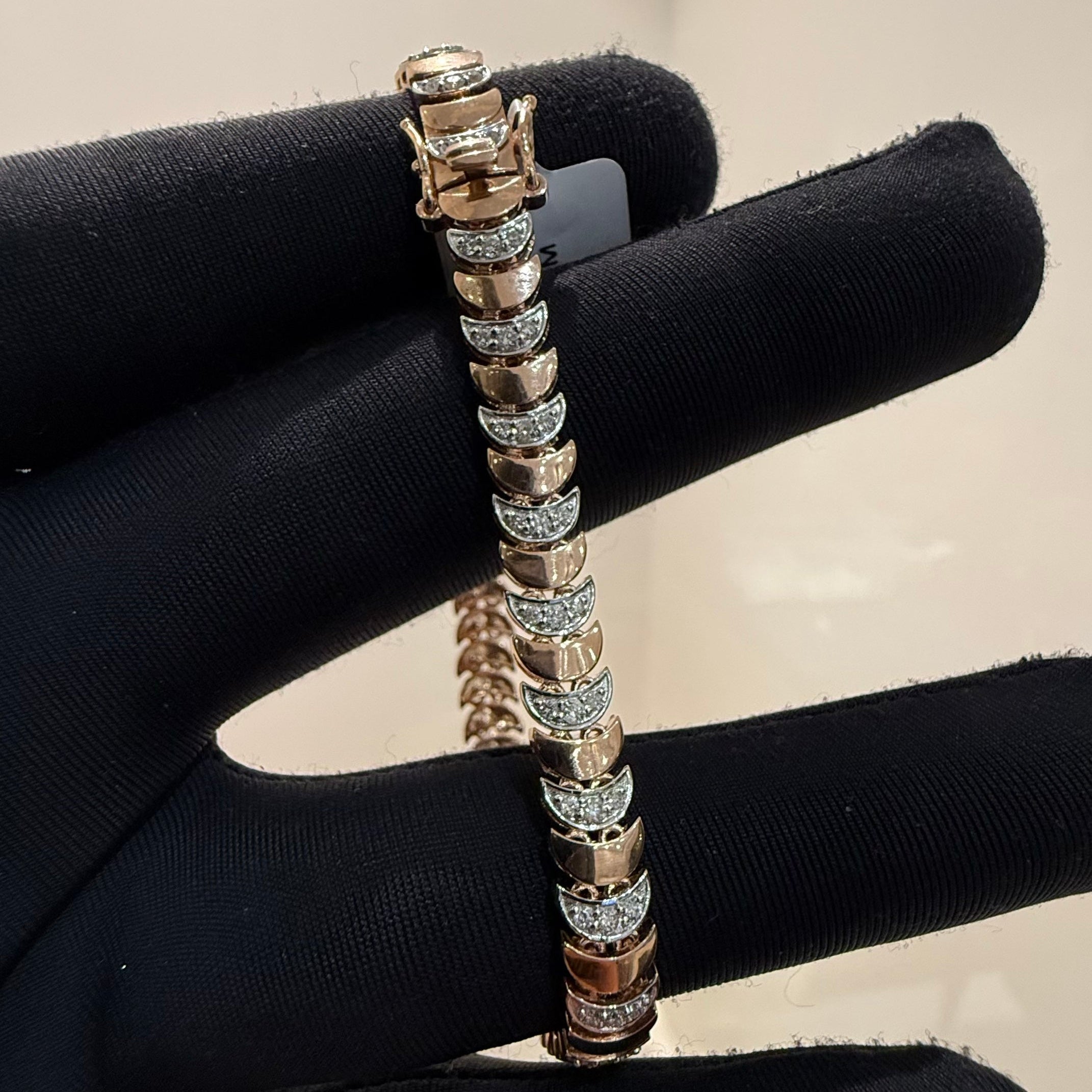 Gold bracelet with diamond accents on a black stand