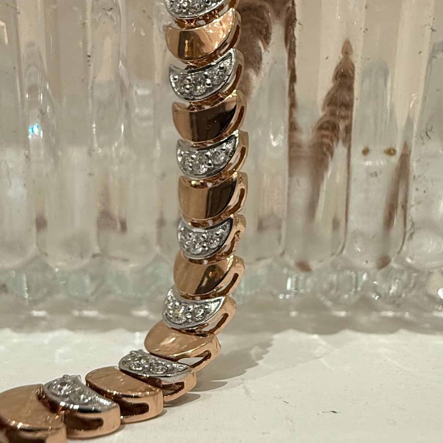 Rose gold bracelet with diamonds on a clear glass background